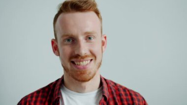 Gri arka planda gülümseyen sıradan giyinmiş çekici bir adamın portresi.