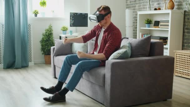 Ξέγνοιαστος μαθητής φορώντας γυαλιά εικονικής πραγματικότητας απολαμβάνοντας το παιχνίδι οδήγησης στο σπίτι — Αρχείο Βίντεο