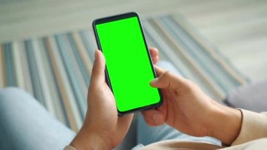 Erkek avuçlarında akıllı telefon ve parmaklarıyla dokunan yeşil ekran.