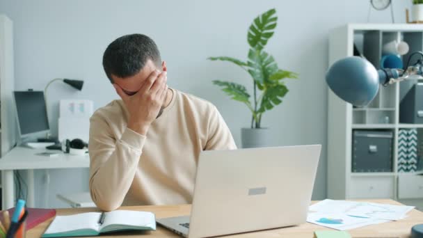 Brunet épuisé travaillant avec un ordinateur à l'intérieur au travail touchant le visage et la tête — Video