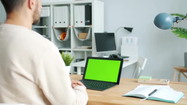 Бізнесмен, дивлячись на зелений екран хром ключ ноутбук працює в сучасному офісі — стокове відео