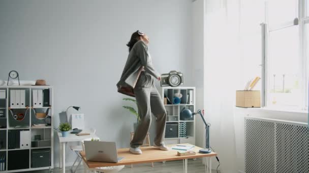 Медленное движение сумасшедшей девушки танцующей в офисе на столе снимая куртку выбрасывая — стоковое видео