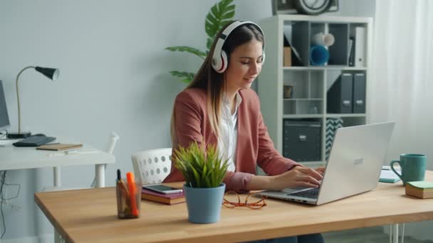 Bella signora in cuffia ascoltare musica in ufficio godendo canzone preferita al lavoro — Video Stock