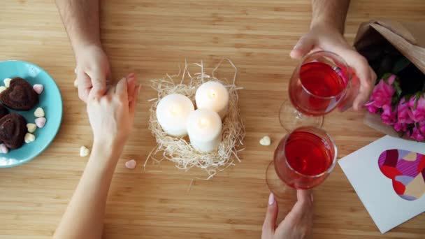 Primer plano de las manos masculinas y femeninas tintinear vasos en el día de San Valentín en la mesa de la cafetería — Vídeo de stock