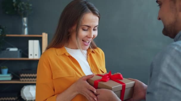 Liebender Mann gratuliert Frau, die Geschenk-Box umarmt, die Liebe zu Hause ausdrückt — Stockvideo
