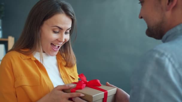 Mujer joven emocionada recibiendo regalo de novio sintiéndose feliz en el apartamento — Vídeos de Stock