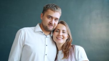 Gri arka planda birbirine gülümseyen güzel bir çift.