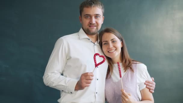 Portrait of beautiful couple holding heart shape lollipops on Valentines day — Stock Video