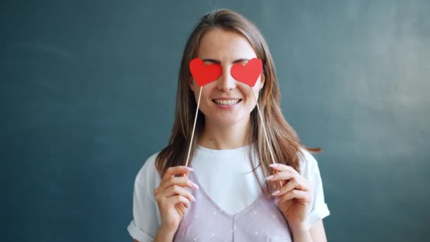 Милая студентка, держащая сердца, скрывая глаза, чувствует себя романтично на День Святого Валентина — стоковое видео