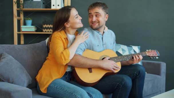 Couple heureux chantant en jouant de la guitare dans l'appartement profiter du temps libre ensemble — Video