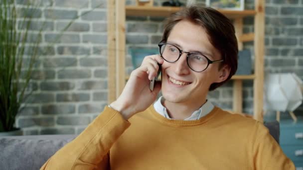 Mladý brunet chatování na mobilním telefonu v bytě těší konverzaci — Stock video