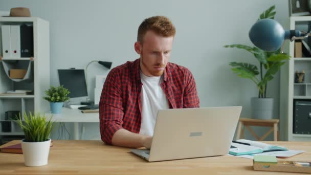 Cansado de gengibre de cabelos cara trabalhando com computador no escritório sentindo dor de cabeça — Vídeo de Stock