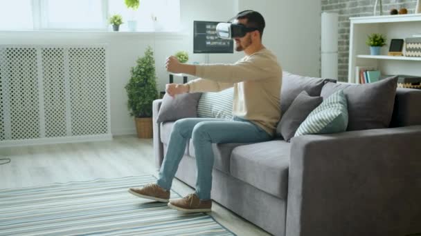 VR 안경을 끼고 현대 장비로 집에서 재미있게 운전하는 즐거움을 누리는 사람 — 비디오