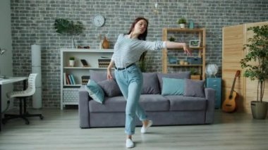 Evde dans eden güzel genç bayan oturma odasında tek başına müzik dinliyor.