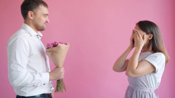 Молодая женщина с закрытыми глазами получает цветы в качестве сюрприза от бойфренда улыбаясь — стоковое видео