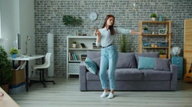 Gündelik kıyafetlerle güzel bir kız evde tek başına dans edip eğleniyor.
