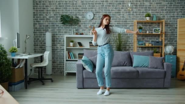 Snygg tjej i avslappnade kläder dansar ensam i lägenheten har kul — Stockvideo