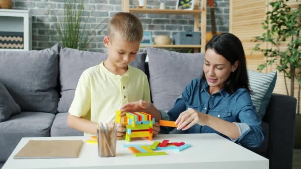 Alegre chica madre jugando con pequeño hijo con bloques de madera y riendo — Vídeos de Stock