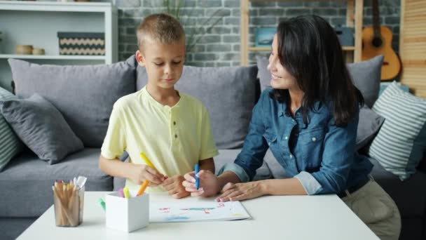 Giovane famiglia mamma e figlio disegno con marcatori in appartamento parlando sorridente — Video Stock