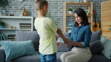 Sevgi dolu çocuk annesine hediye veriyor. Öpüşüyor, evde sürpriz yapıyor.