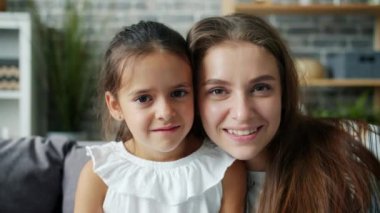 İçerideki kameraya gülümseyen anne ve kızının mutlu genç portresi.