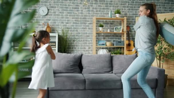 Mała dziewczynka i kochająca matka walczą poduszki śmiejąc się relaks w domu razem — Wideo stockowe