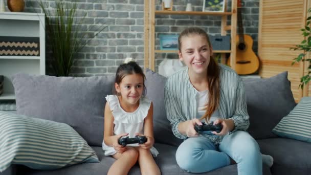 Μητέρα και κόρη παίζουν βιντεοπαιχνίδι στο σπίτι διασκεδάζοντας γελώντας μαζί — Αρχείο Βίντεο