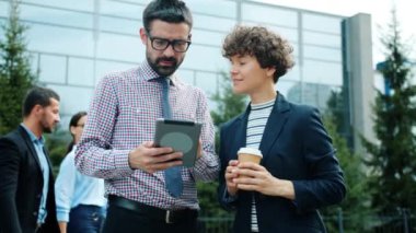 Tablet kullanan hırslı insanlar ofis yakınlarında iş konuşuyorlar.