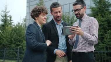 Dışarıda tablet tutmaktan bahseden genç ve mutlu meslektaşlar yavaş hareket ediyor.