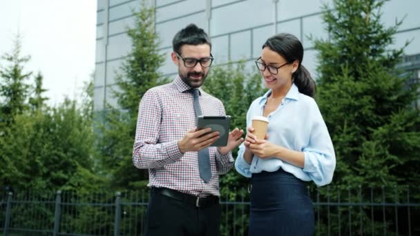 Empresarios ambiciosos discutiendo negocios fuera y trabajando con tableta — Vídeos de Stock