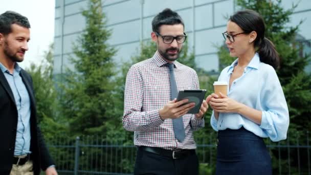 Businesspeople talking using tablet outside near office center discussing business — ストック動画