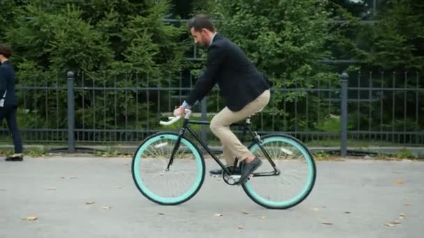 Gestor bonito pessoa ativa andar de bicicleta para prédio de escritórios pela manhã — Vídeo de Stock