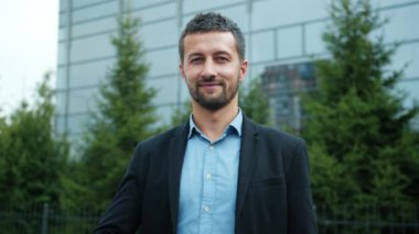 Hırslı bir adam arka planda iş merkeziyle baş parmak işareti yapıyor.