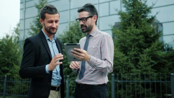 Uomini d'affari con tablet che parlano usando internet all'aperto in strada sorridendo — Video Stock