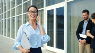Hırslı iş kadını cep telefonuyla konuşuyor. Şehir dışında yürüyor.