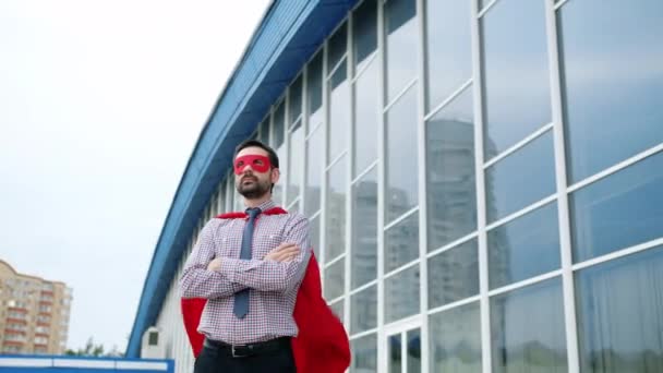 Portret wpływowego biznesmena w czerwonej pelerynie i masce na zewnątrz w wietrzny dzień — Wideo stockowe