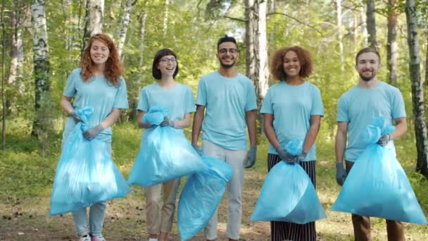 Multietnisk grupp av miljöaktivister i skogen med soppåsar tittar på kameran — Stockvideo