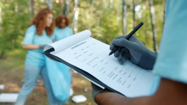 Gros plan main dans la main prendre des notes dans le rapport des bénévoles pendant le nettoyage dans le parc 