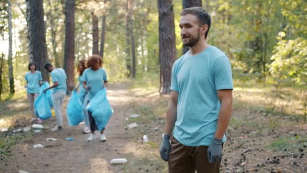 Retrato de jovem homem alegre voluntário na floresta durante a limpeza do dia da terra — Vídeo de Stock