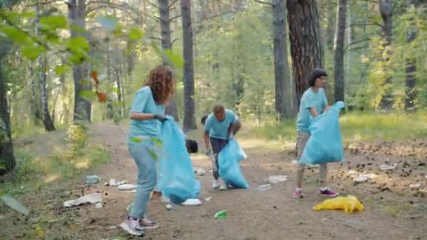 Studenter flickor och killar städa skogen på jorden dag samla skräp i plastpåsar — Stockvideo