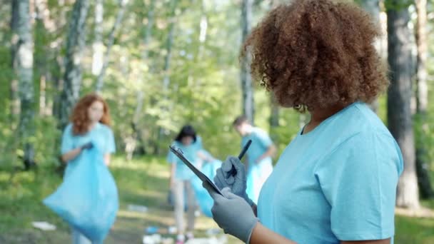 Retrato de voluntario afroamericano ocupado con el papeleo en bosques contaminados — Vídeo de stock