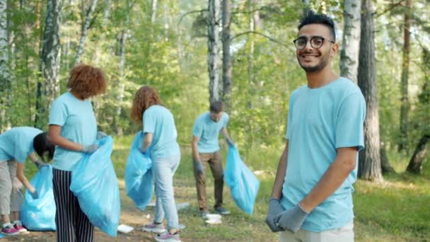 Retrato de eco-ativista árabe vestindo camiseta voluntária e luvas na floresta — Vídeo de Stock