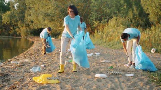 Multi-etnische groep studenten die het strand schoonmaken tegen vervuiling tijdens de dag van de aarde — Stockvideo