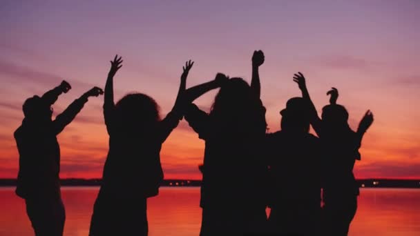 Χαρούμενοι μαθητές που χορεύουν στην παραλία το ηλιοβασίλεμα χαλαρώνοντας στο υπαίθριο πάρτι μαζί — Αρχείο Βίντεο