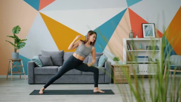 Hermosa chica haciendo ejercicios de yoga en casa estirando el cuerpo en casa en el suelo — Vídeos de Stock