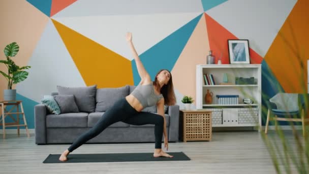 Langzame beweging van flexibele jonge dame die thuis yoga beoefent in mooi appartement — Stockvideo