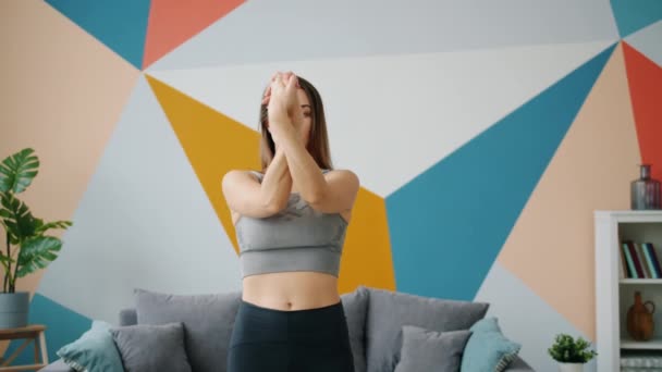Гибкая девушка растягивая руки во время практики йоги в домашних условиях сосредоточены на упражнениях — стоковое видео