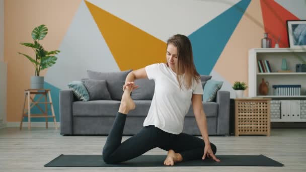 Slow motion van jonge vrouw stretching lichaam met yoga oefeningen in modern huis — Stockvideo