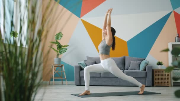 Zeitlupe eines unbeschwerten Mädchens in Sportbekleidung, das allein zu Hause Yoga-Asanas macht — Stockvideo