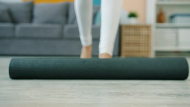 Low shot van yoga student uitrollen mat dan doen oefeningen blootsvoets thuis — Stockvideo